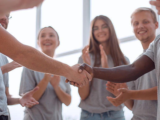 Young people stand in a circle and shake hands.