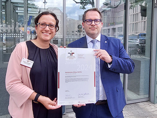 Susann Schwarze and the Rector hold up the certificate for a family-friendly university.