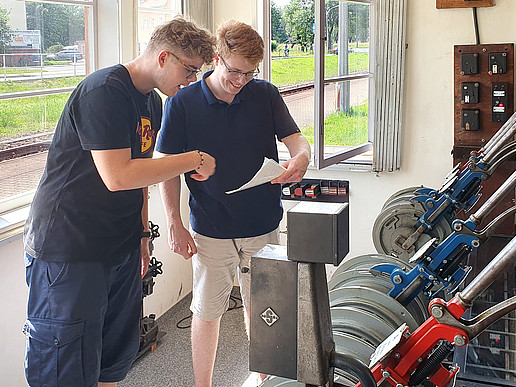 In the mechanical signal box at the Zittau Süd training station, two students adjust the route into the mountains with a lot of muscle power and look at plans.