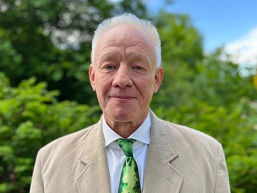 Prof. Kästner stands outside on the Görlitz campus in a suit and smiles at the camera.