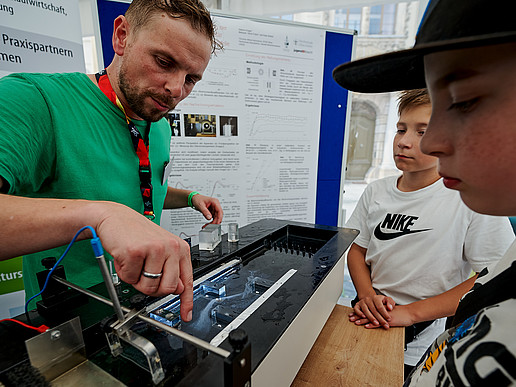 Ein HSZG-Mitarbeiter erklärt Schüler am Stand Strömungstechnik.