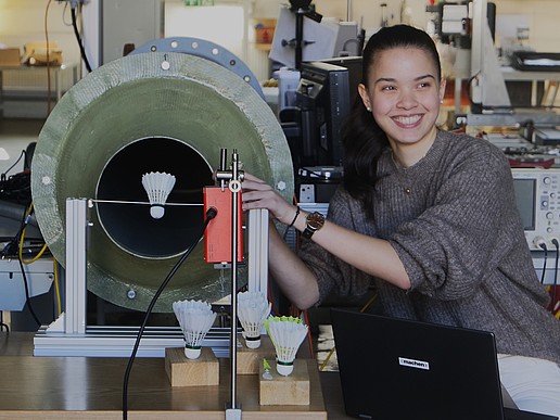 Helena is squatting next to a flow system with a shuttlecock stretched out in front of it.